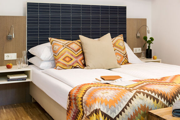 Ein Bett mit bunt gemusterter Bettwäsche im Boutiquehotel Stadthalle in Wien