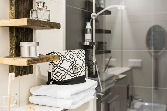 Eine schwarz-weiße Toiletttasche steht auf einem weißen Handtuch in einem Badezimmer