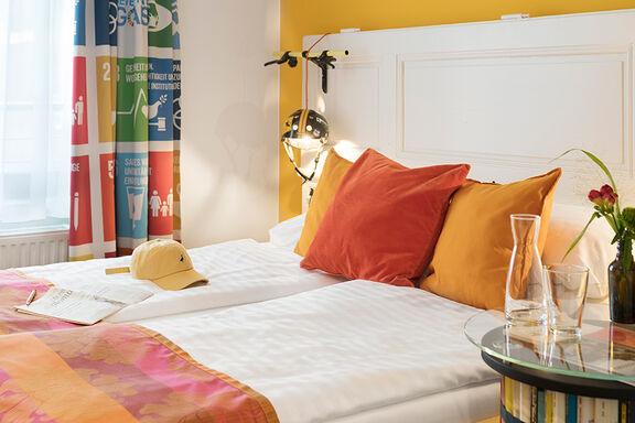 A bed with orange bedclothes in the boutique hotel Stadthalle in Vienna