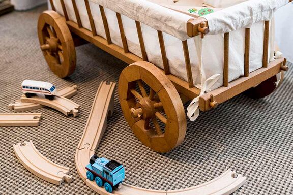 Verschiedene Kinderspielsachen aus Holz liegen auf einem Teppichboden im Boutiquehotel Stadthalle in Wien