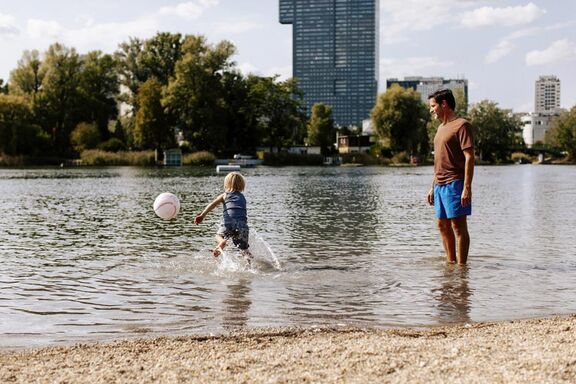 Mann mit Kind im Fluss spielen Ball