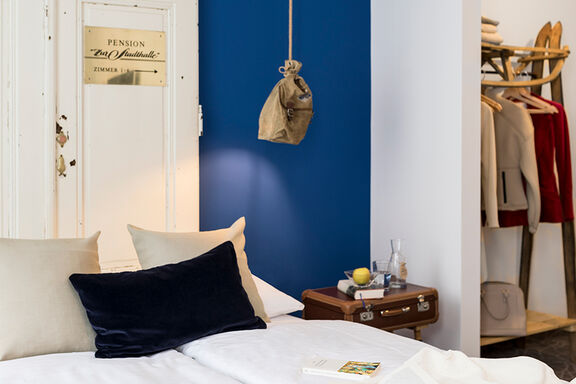 Ein Bett mit weißer Bettwäsche vor einer blauen Wand im Boutiquehotel Stadthalle in Wien