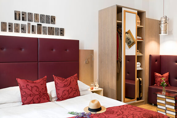 Blick in ein Zimmer im Boutiquehotel Stadthalle mit roter Bettwäsche