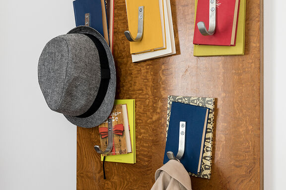 A gray hat hangs on a coat hook