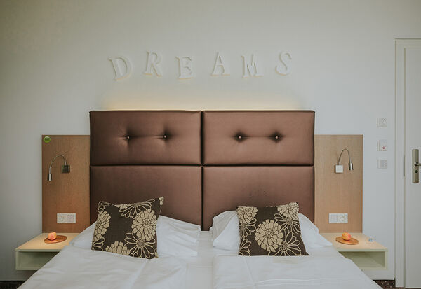 Barrierefreies Zimmer Bett frontal mit Dreams Überschrift an der Wand