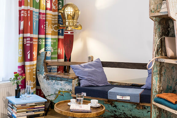 Ein Sofa aus einem alten Holzboot steht neben einem Kaffeetisch aus Holz