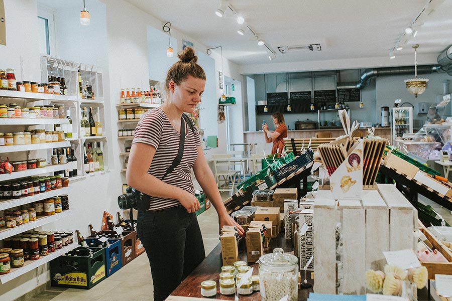Frau steht mit einer Kamera im Lebensmittelladen